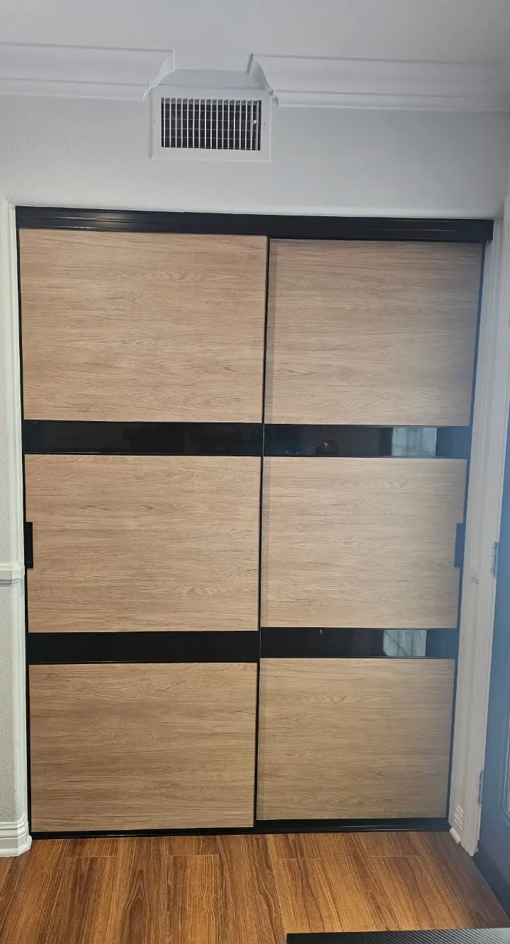 Sliding closet doors combining oak-look panels with bands of black glass in a dark frame
