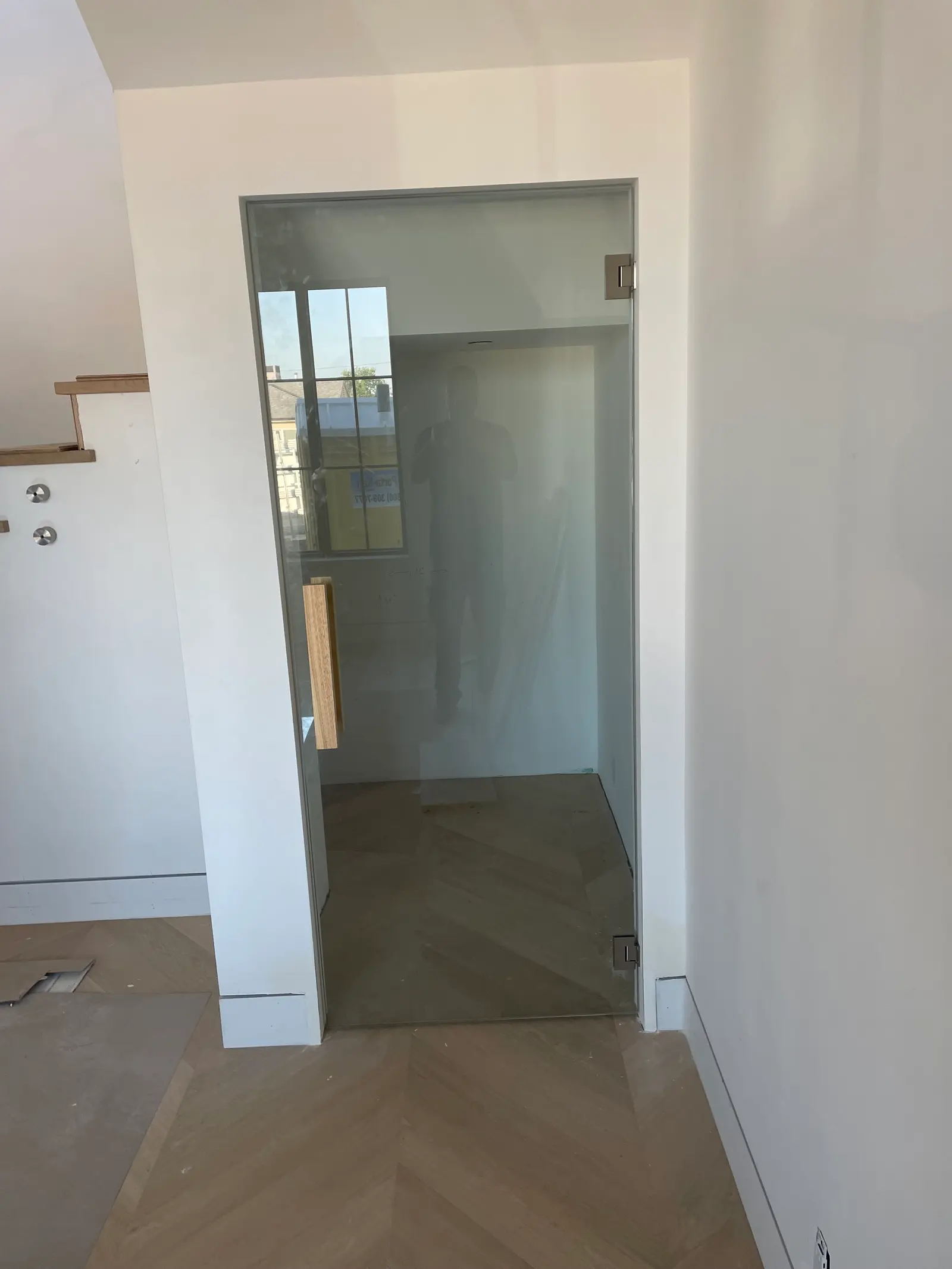 Single frameless glass door with a wood pull opening into a walk-in pantry