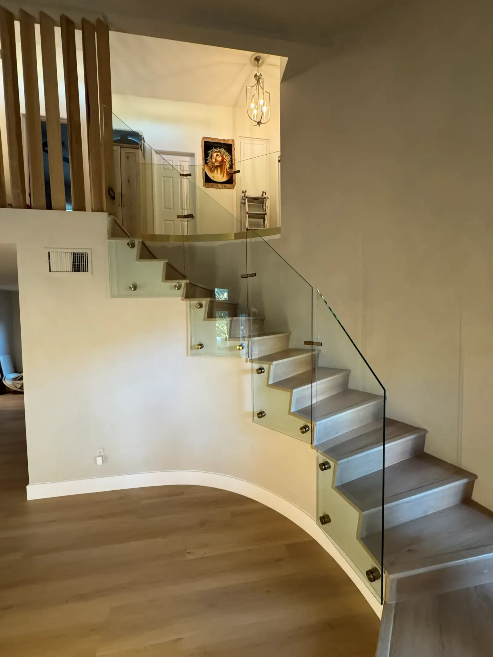 Curved glass railing with brass standoff fittings following a winding staircase