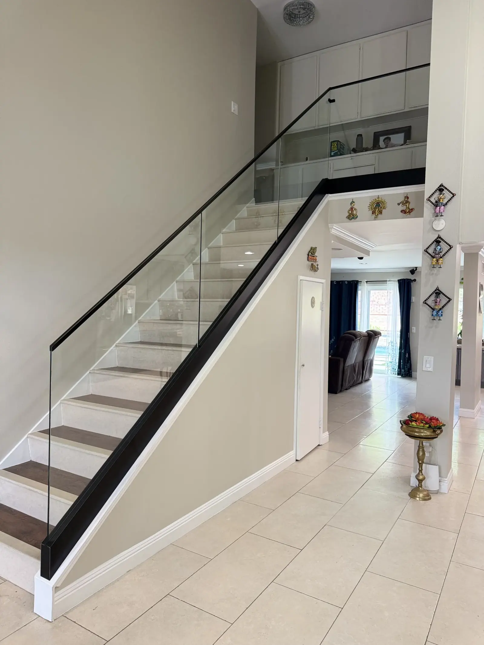 Glass stair railing with a slim black cap rail in a two-story foyer