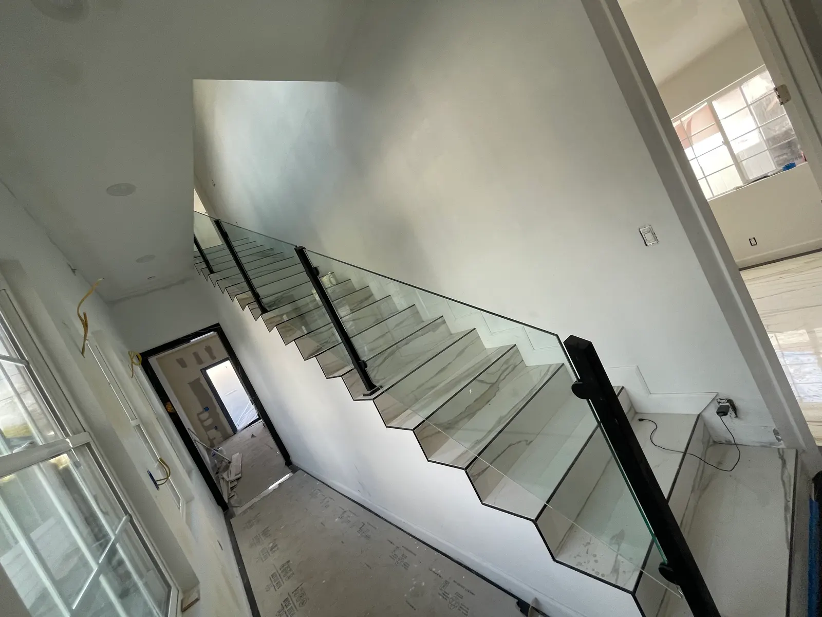 Frameless glass stair railing with a slim black cap rail following a straight run of stairs