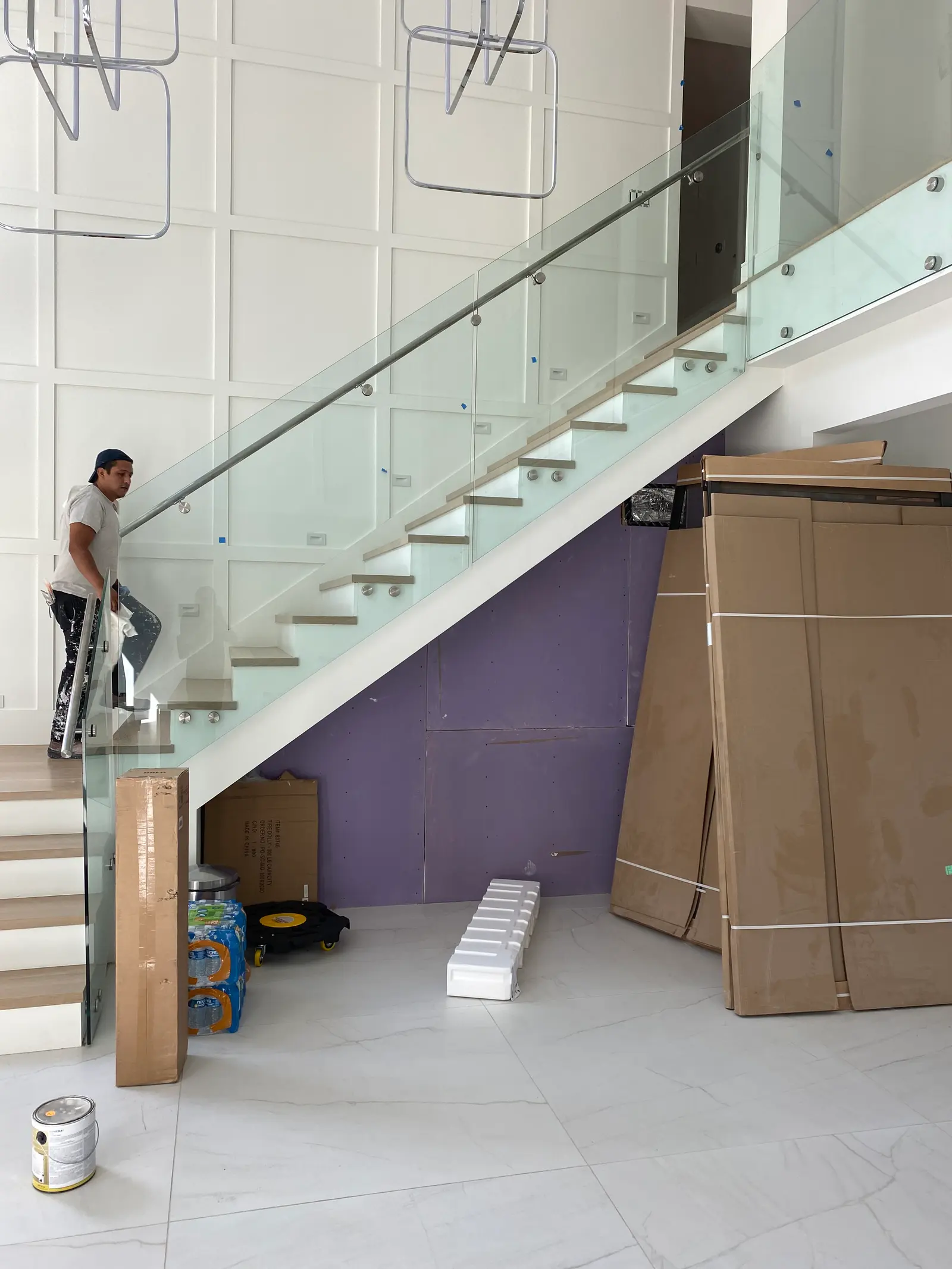 Glass stair railing on stainless standoffs with a slim metal handrail, against a panelled wall