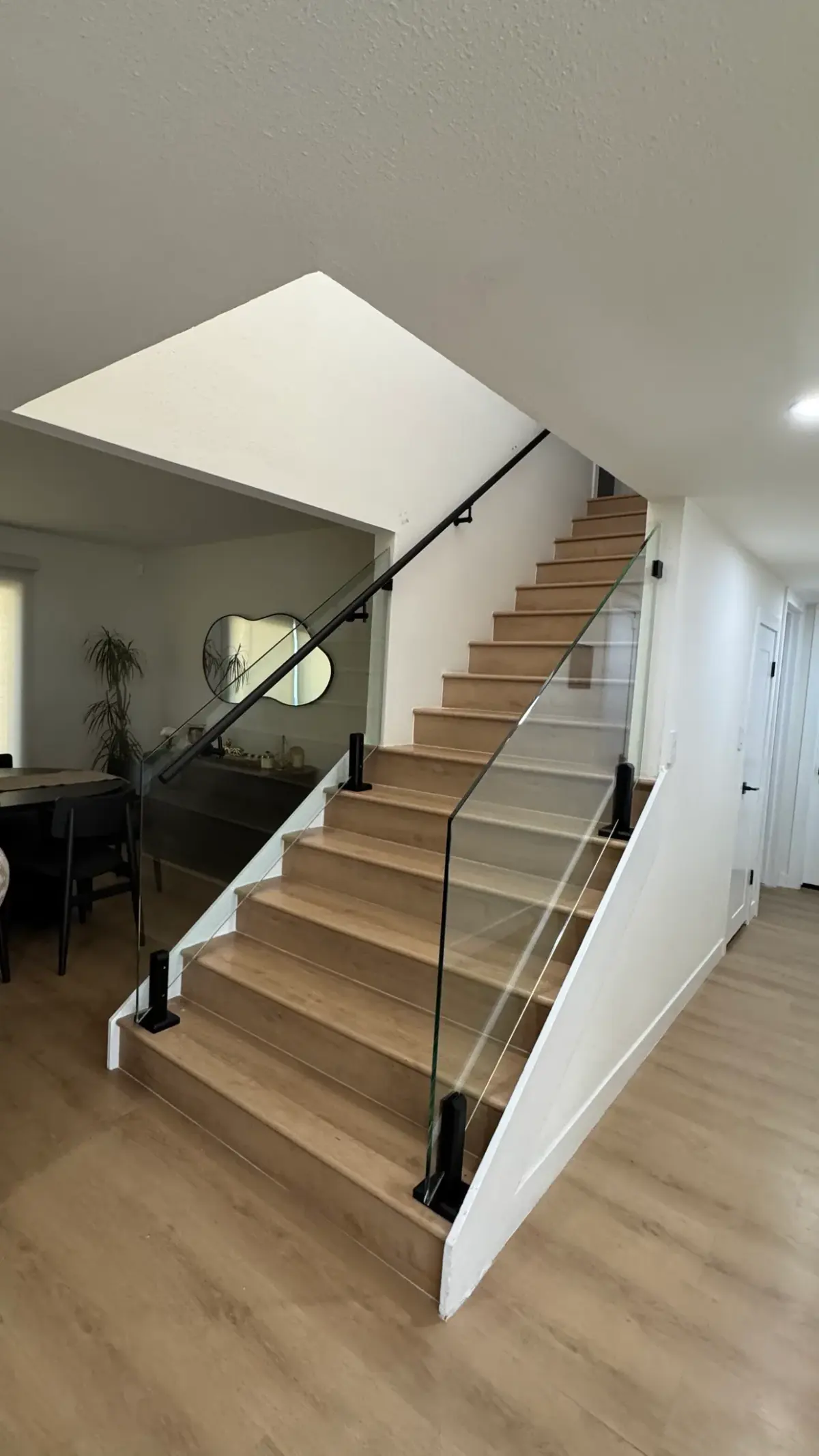 Glass stair railing with matte-black posts and handrail on oak treads
