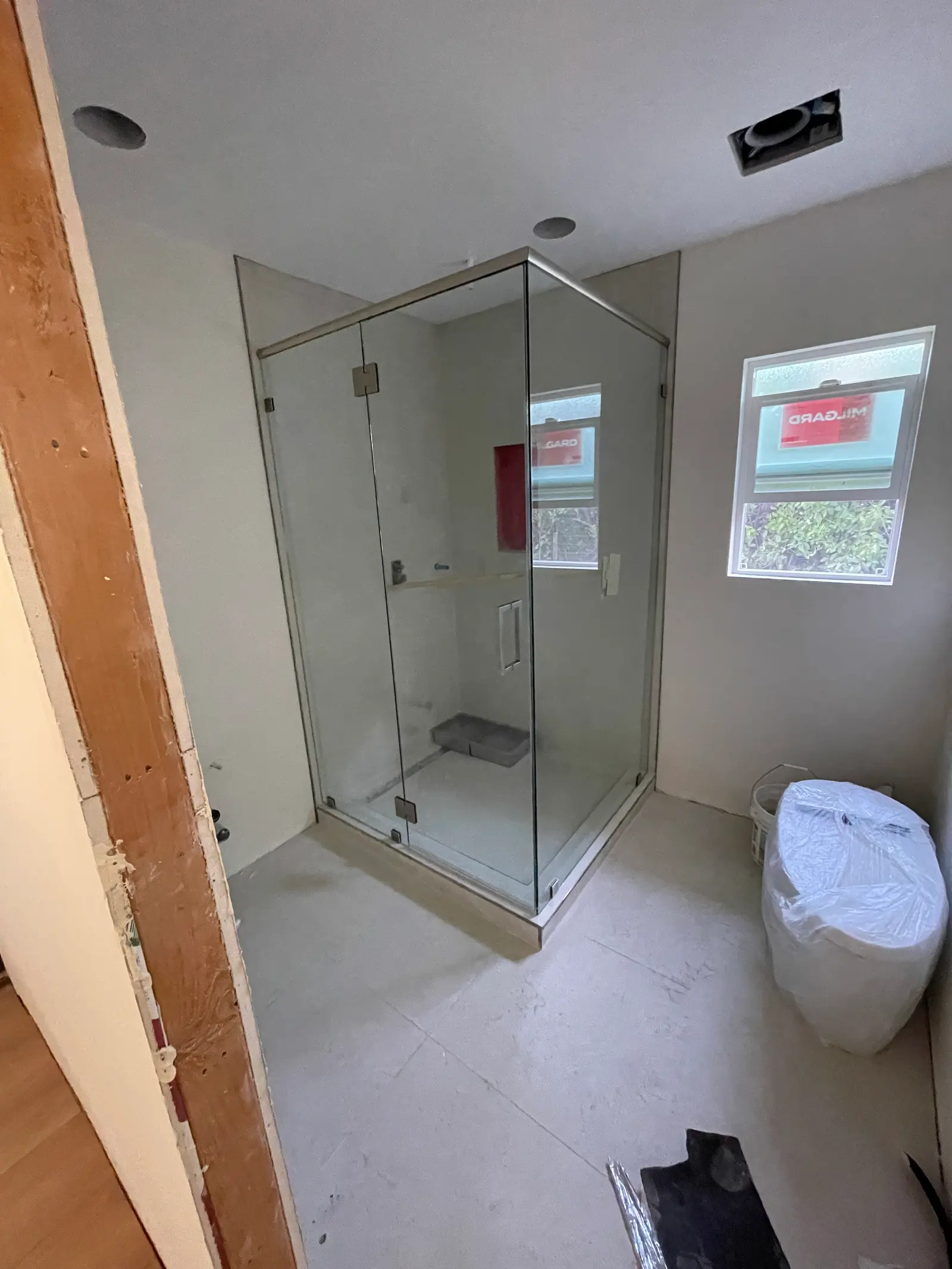 Frameless corner shower enclosure with chrome hardware and a built-in stone bench