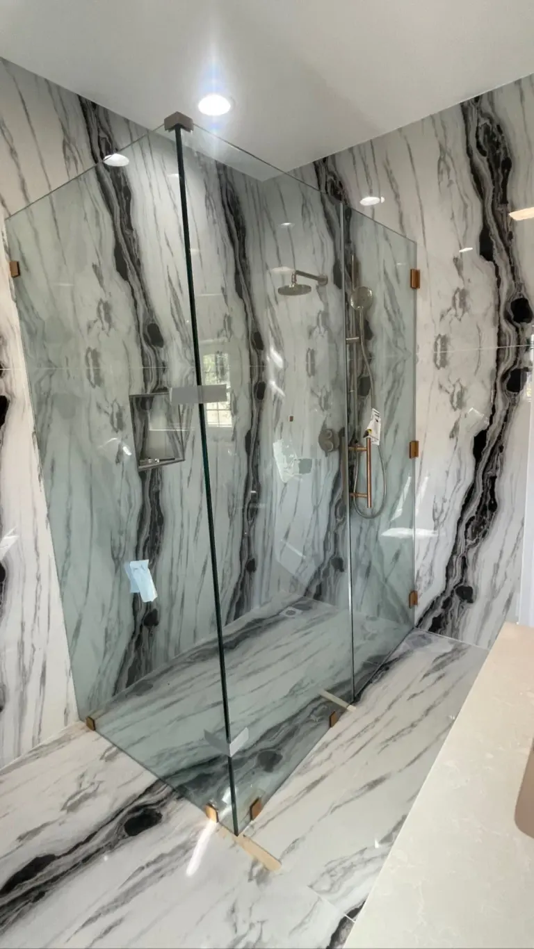Frameless corner glass panels in a panda-marble shower with black-and-white veining